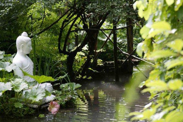 Una statua di Buddha medita davanti un laghetto del Giardino di Villa Pennisi, ad Acireale Una statua di Buddha medita davanti un laghetto del Giardino di Villa Pennisi, ad Acireale