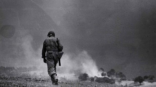 Soldato attraversa un campo in missione di ricognizione, nei pressi di Troina - Sicilia, Agosto 1943, foto Robert Capa